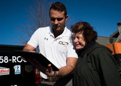 Man showing tablet to a woman outside, with a truck in the background.