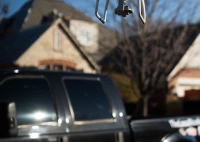 Rear view of a black truck with a residential house in the background on a sunny day.