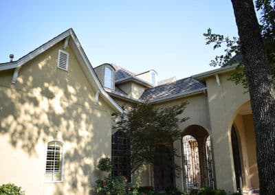 Elegant two-story yellow house with a detailed entrance and lush landscaping.