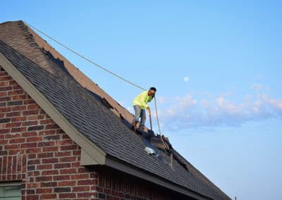 Roofer repairing a residential roof under a clear sky with the moon visible.