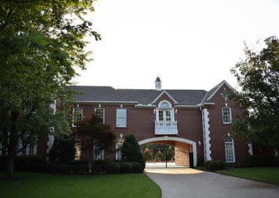 Elegant brick mansion witharched windows and manicured lawn under clear sky.