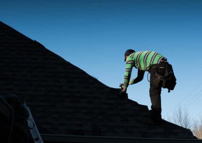 Roofer repairing a sloped roof under a clear blue sky.